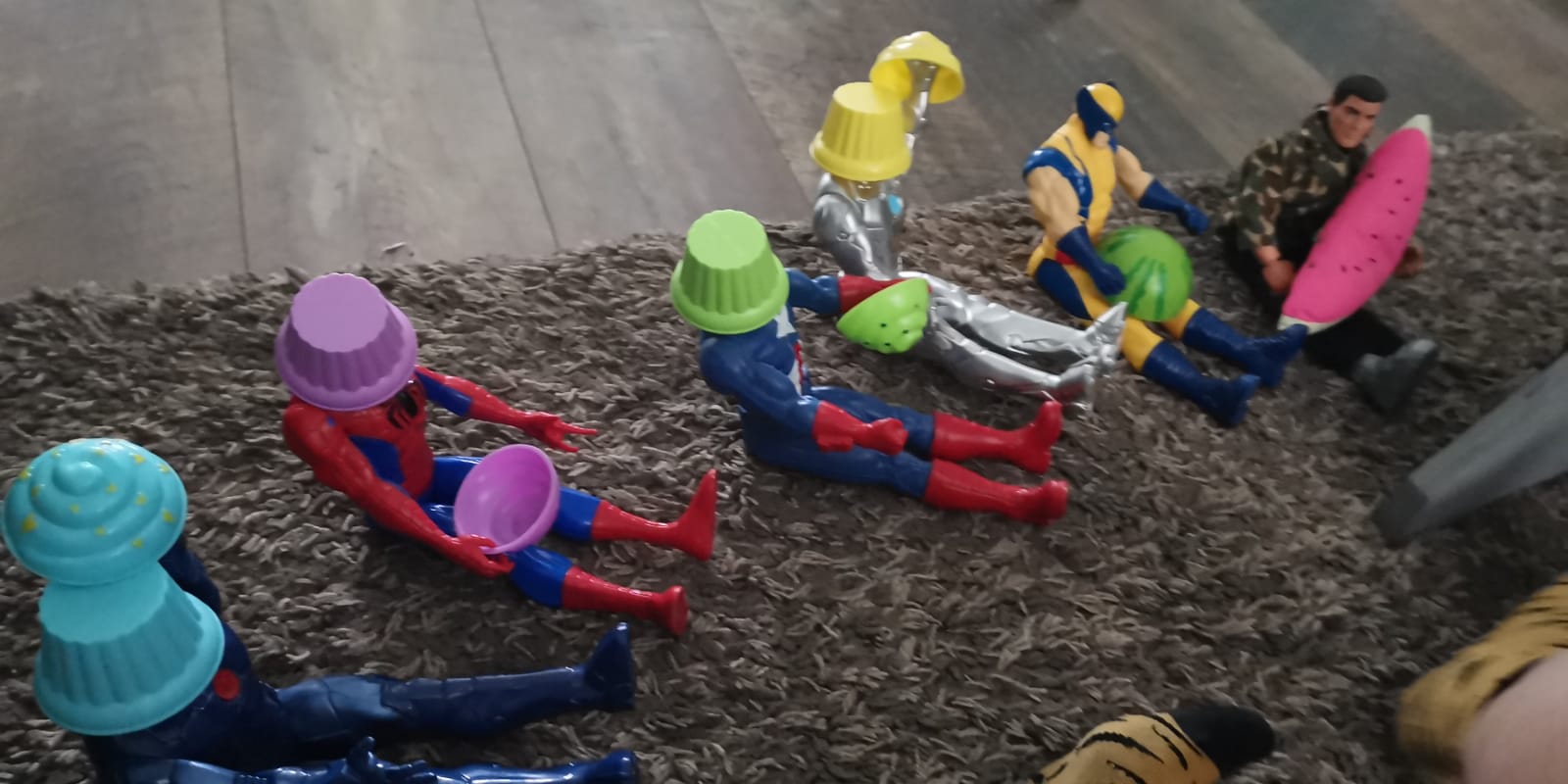 Image of toy superheroes with plastic cupcakes on their heads